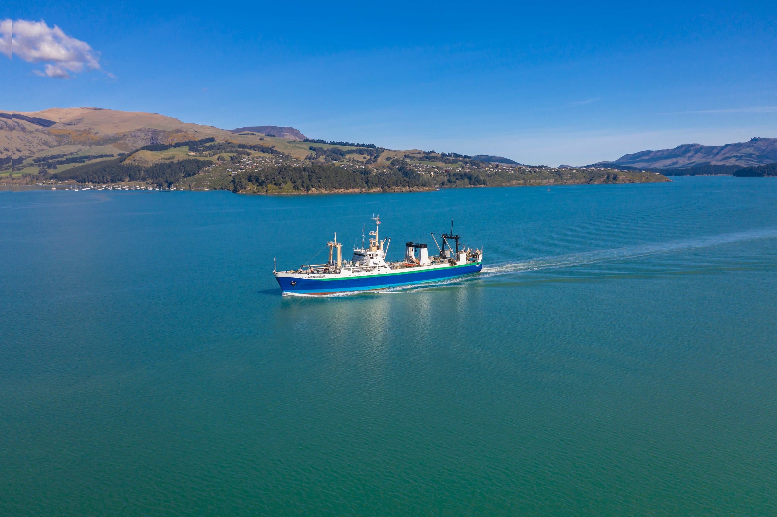 An Independent Fisheries vessel under way in turquoise New Zealand coastal waters